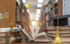 books on a table in a library with a graduation cap