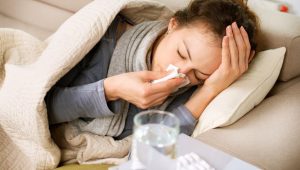 a sick person laying in bed blowing their nose